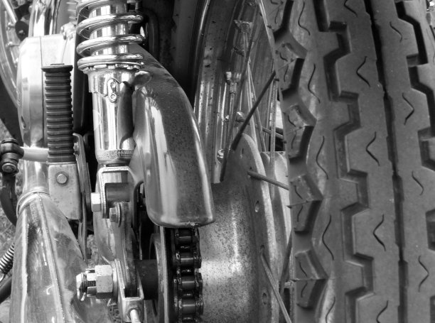 一个老式摩托车的近后视图轮胎踏轮辐条驱动链和闪亮的铬弹簧图片下载