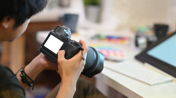 摄影师在创意的工作场所用专业的相机工作和检查。图片下载