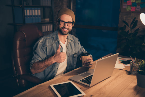 照片自信的家伙工作到深夜享受新鲜的咖啡饮料穿着休闲装坐在现代的办公室图片下载