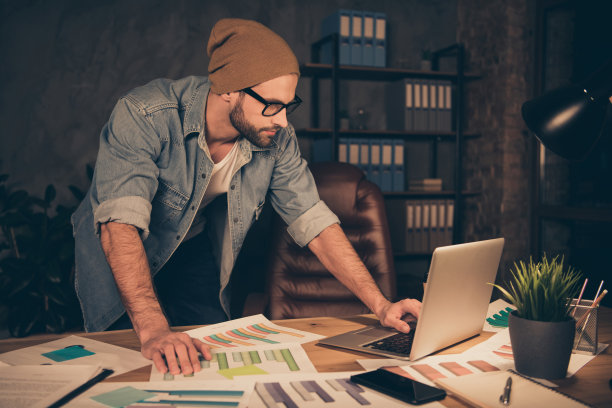 晚上工作的照片老板家伙读合同穿休闲装站在桌子旁边在现代的办公室图片下载