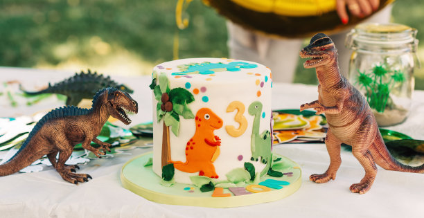 孩子的生日聚会。用恐龙雕像装饰的白色乳香蛋糕图片下载