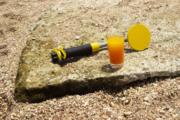 岩石上的橙汁与水下金属探测器照片：寻宝与探险之旅图片下载