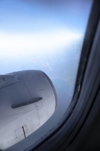 飞机窗口俯瞰着美丽的云朵和地球。假日飞行中的日落。旅游主题。库存图片图片下载