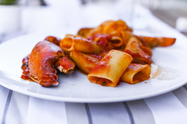 带刺龙虾和番茄酱的意大利面。餐厅的海鲜午餐和一杯白葡萄酒。蓝色和选择性的聚焦在照片上。图片下载