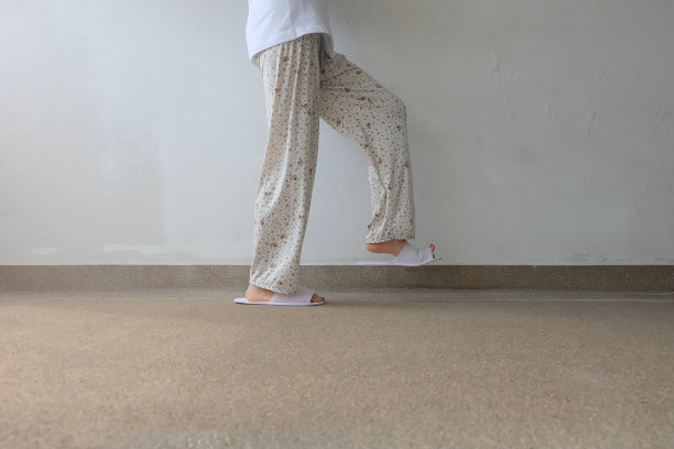 混凝土背景下的自拍拖鞋，俯视图。漂亮的年轻女子，穿着白色拖鞋和裤子。清暖的家凉鞋。图片下载