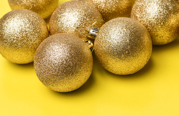 金色的圣诞球玩具躺在黄色的背景上图片下载