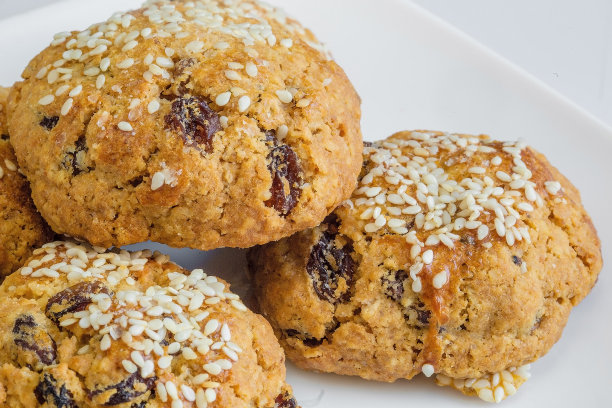 特写微距照片的一堆新鲜烘烤的家做耐嚼燕麦饼干与葡萄干孤立在白色的背景图片下载