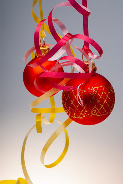 一对挂在灯光背景上的红色圣诞球。图片下载