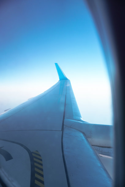 飞机窗口俯瞰着美丽的云朵和地球。假日飞行中的日落。旅游主题。库存图片图片下载