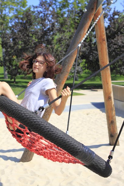 年轻快乐的女孩坐在绳子做成的秋千上。一个少女正在荡秋千。一个青少年在公园的操场上玩得很开心。图片下载