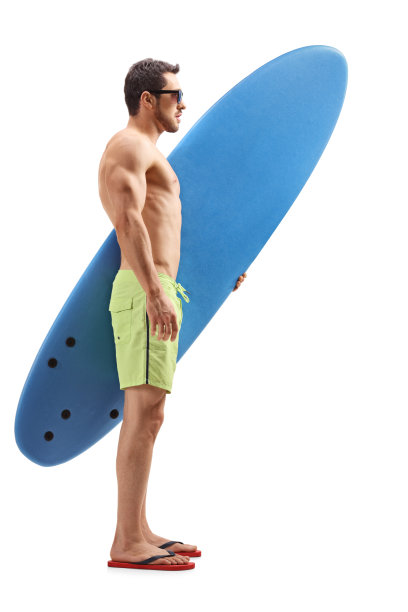 一个年轻人拿着冲浪板站在那里等着图片下载