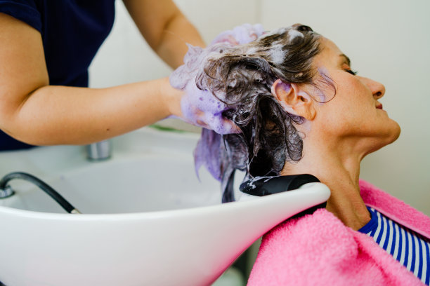 美发师在沙龙里为女顾客洗头发，用洗发水在头上涂护发素图片下载