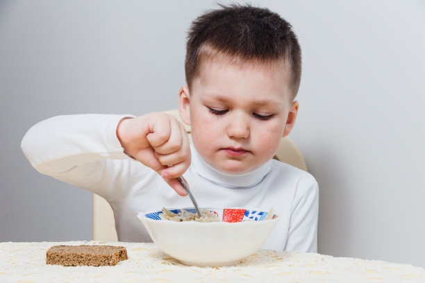 可爱的小男孩在白色背景的桌子上吃东西图片下载