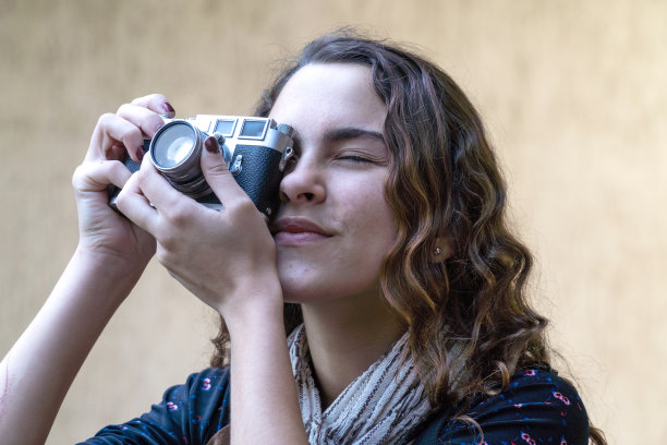 年轻漂亮的女孩拍照与数码复古相机在花园在阳光明媚的夏天与清楚的墙背景。旅行、艺术、自由、摄影、青春和科技理念。图片下载
