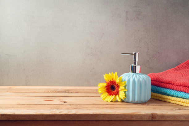 浴巾和肥皂瓶放在浴室墙壁背景的木桌上图片下载