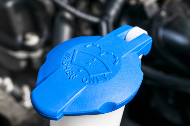 汽车挡风玻璃刮水器清洗喷淋水箱蓝色瓶盖在汽车发动机空间。汽车详细。汽车内部。安装在前引擎盖下靠近汽车引擎。图片下载