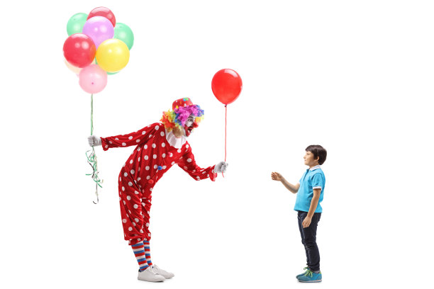 小丑给一个男孩一个气球，另一只手拿着一堆气球图片下载