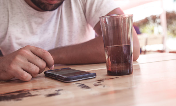 一名男子坐在咖啡馆里使用智能手机。图片下载