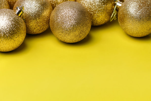 金色的圣诞球玩具躺在黄色的背景上图片下载