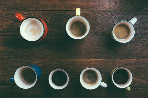 木质背景上彩色杯子里的咖啡，俯视图图片下载