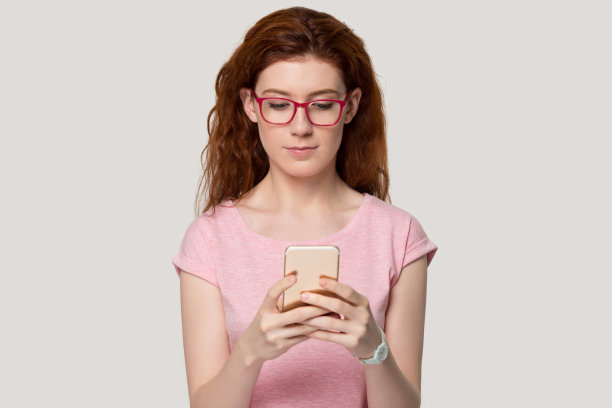 漂亮的红发女人看着手机屏幕拍摄工作室图片下载