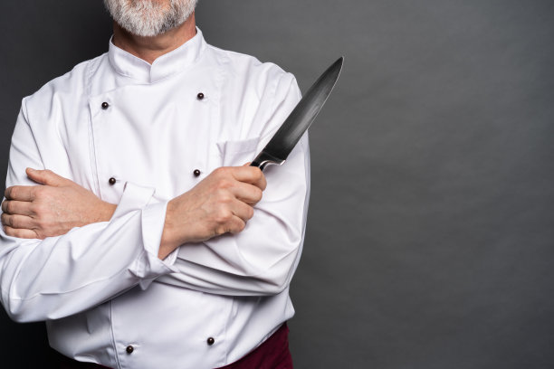 一个成熟的厨师厨师的肖像拿着刀孤立在一个黑色的背景。图片下载