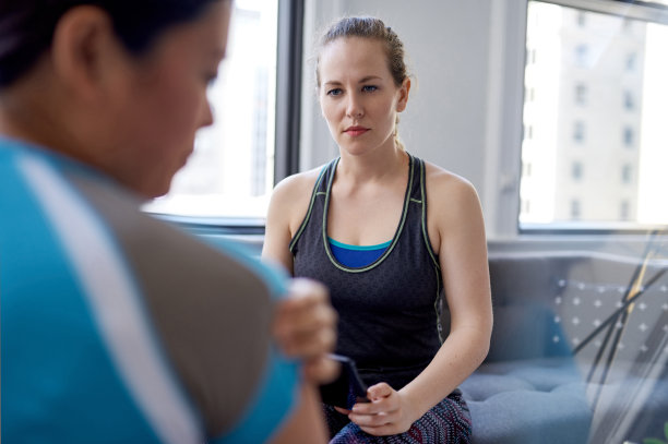一名白种女性物理治疗师在健康评估咨询期间与一名中国中年女性患者交谈，并在平板电脑上做记录图片下载