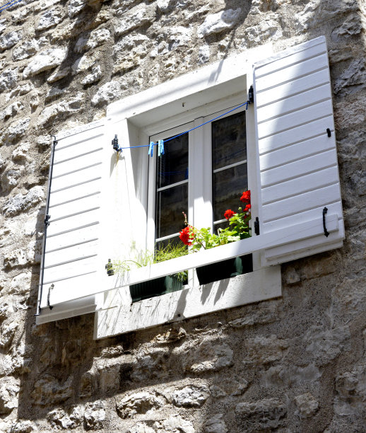 复古风格的窗户，白色百叶窗，窗台上的天竺葵和洗衣绳与晾衣夹图片下载