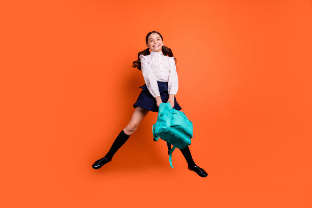 整个长度的身体尺寸视图照片可爱的梦幻迷人可爱的孩子握着手放松后的教室靴子长袜连衣裙白色的衣服衬衫孤立的橙色背景图片下载