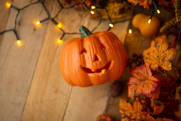 万圣节的南瓜与树叶在一个古老的木制桌子上发光的灯。从以上观点。副本的空间。秋的心情，和大气的照片。图片下载