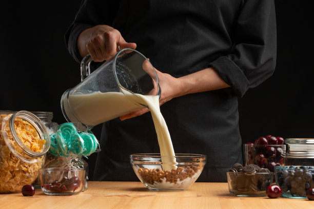 牛奶什锦早餐是在盘子里倒入牛奶和麦片，用来做早餐。健康健康的食物，素食主义，以黑色为背景。水平的照片图片下载