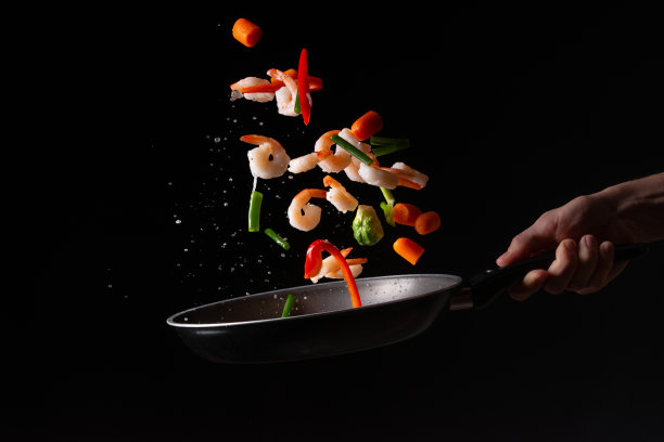 特写，海鲜，厨师用新鲜鲜亮的蔬菜在煎锅里煮虾，烤。以黑色为背景进行设计，菜单、餐厅、东方料理、健康食品。水平的照片图片下载