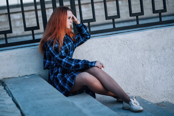 宁静的女孩独自站在河堤的栅栏前。图片下载