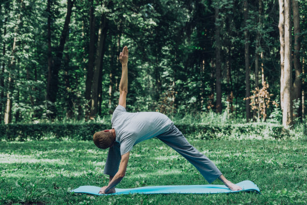 在公园的绿草地上，男人伸展着双手和双腿。图片下载