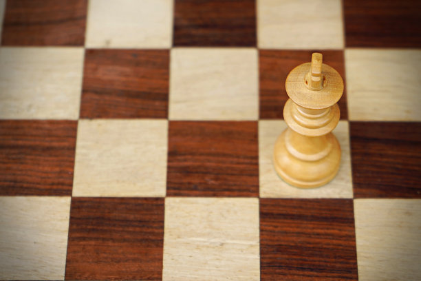 水平股票照片的一个国王棋子在一个纹理木质瓷砖象棋板图片下载