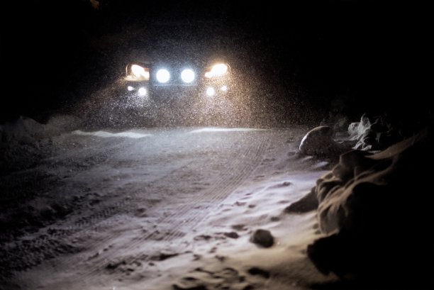 晚上在雪地里开车时，车灯在雪地上图片下载