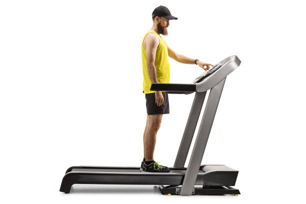 穿着运动服的大胡子男人站在跑步机上按按钮图片下载