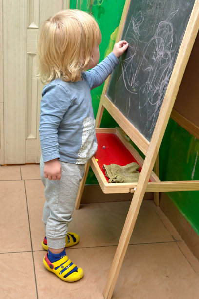 两岁的金发小孩用粉笔在黑板上画画图片下载