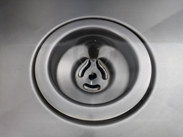 漩涡水，漩涡在排水孔上旋转，在不锈钢背景上形成美丽的抽象圆圈。水流入排水孔，场深较浅图片下载