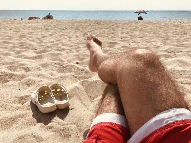 靠近沙滩上的男性腿图片下载