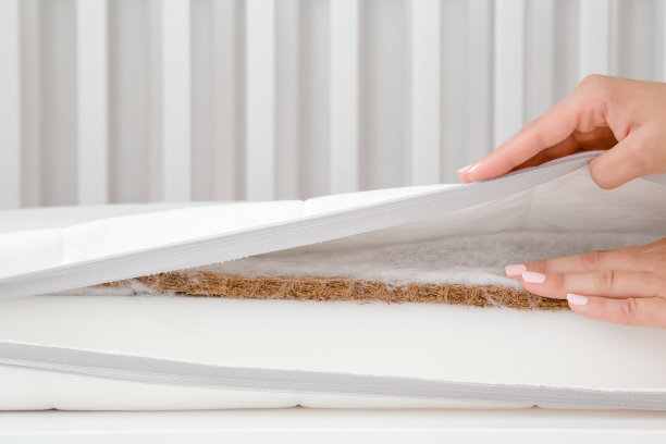 女人的手触摸不同层次的新白色床垫。妈妈检查婴儿床的软硬。选择最好的类型和质量。特写镜头。图片下载