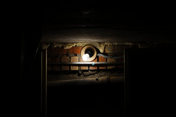 在一间黑暗的房间里，一个灯泡照在一堵旧砖墙上。图片下载