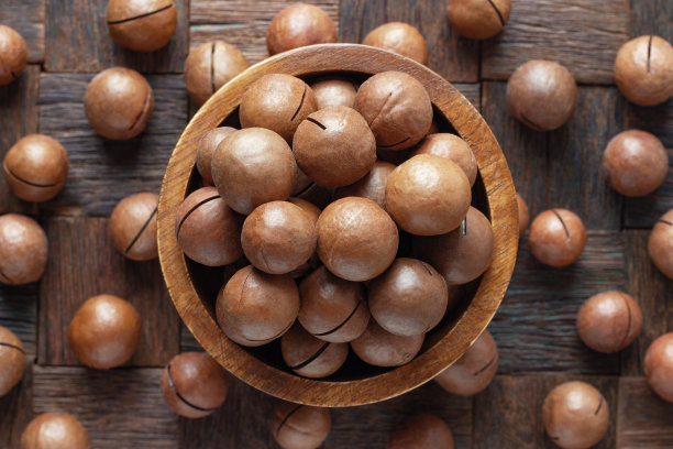 去壳的澳洲坚果在木碗，俯视图。图片下载