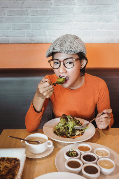 亚洲女性在吃盘子里的沙拉时很开心。专注于脸图片下载