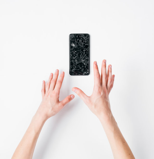 情感的手穿过撕破的洞纸白色的背景与一个破碎的智能手机图片下载