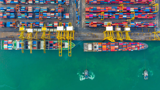 集装箱船在工业港口工作，通过集装箱船在公海进行国际业务进出口物流和运输，鸟瞰集装箱船装卸。图片下载