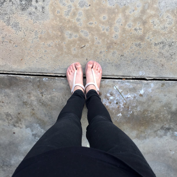 脚和腿的自拍与鞋在道路街道，俯视图。年轻女子穿着米色凉鞋图片下载