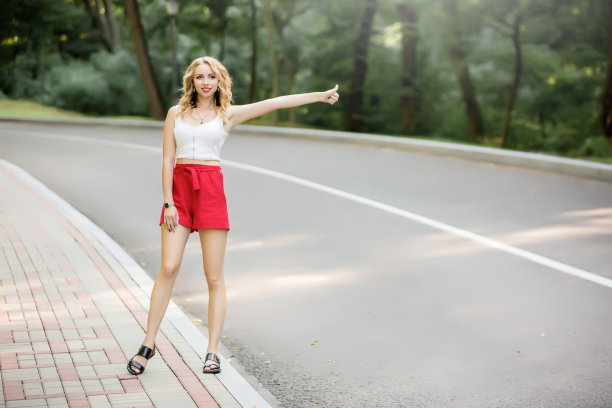 夏天的生活方式，漂亮的年轻迷人的旅行者女孩穿着红色短裤，独自走在欧洲的城市中心，试图赶上出租车到机场航站楼或火车站。图片下载