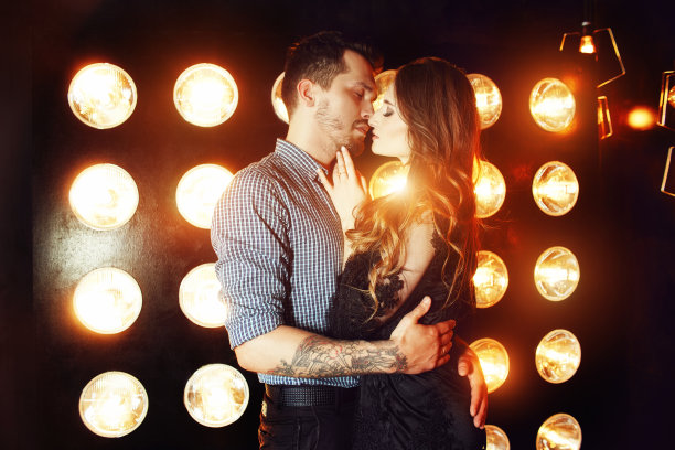 在明亮的灯光背景下，美丽的情侣拥抱在一起。一个金发女孩和一个短发男孩的工作室肖像照片。情人节。爱的夫妻。家庭幸福图片下载