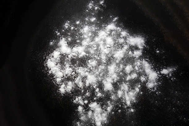 黑色背景上的白色粉末。孤立的抽象图案用于烹饪，医药或化学设计装饰。近距离的水晶堆随机纹理图片下载